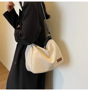 Detail of large beige tote bag featuring leather logo patch and woven rope shoulder strap