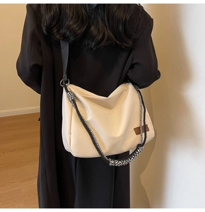Detail of off-white tote bag showing double shoulder straps and side leather logo patch