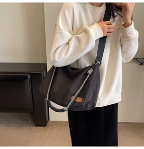 Detail of large black tote bag with dual shoulder straps and a brown leather patch