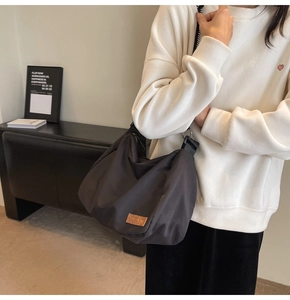 Close-up of the black nylon hobo bag showing the brown leather logo and soft fabric texture