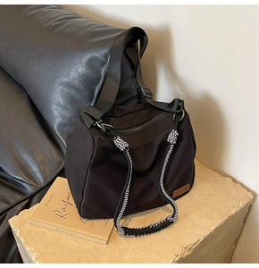 Close-up of black nylon tote bag with decorative black and white ropes on stone surface