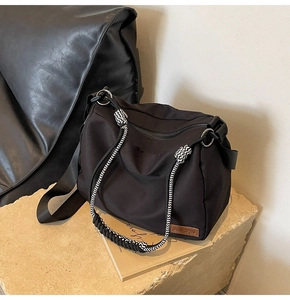 Detail of black nylon tote bag featuring JINGPIN leather label and woven handle decoration