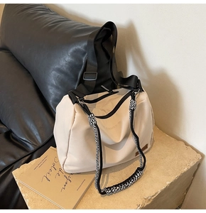 Close-up of beige tote bag featuring black woven rope detail and brown leather logo patch