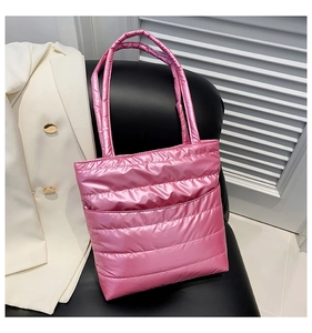 Chic pink quilted tote bag with metallic finish displayed on a black leather chair
