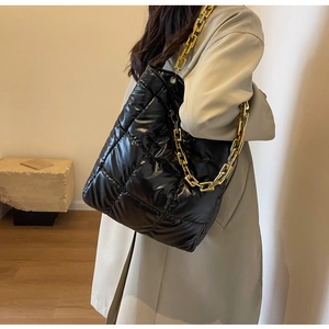 Close-up of quilted black tote bag with premium gold chain strap on shoulder