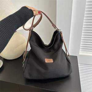 Large black canvas tote bag with brown leather straps for commuting and daily use
