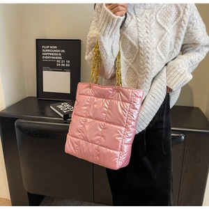 Detail of pink quilted tote bag featuring a chunky gold chain handle and shiny finish