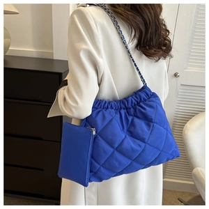 Detail van de felblauwe gewatteerde schoudertas met ketting en mini-tasje