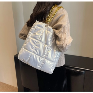 Close-up of silver quilted puffer tote bag with decorative chunky gold chain strap