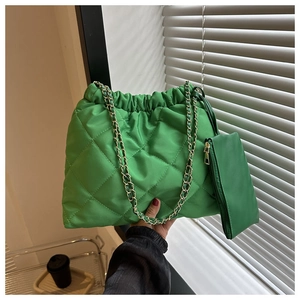 Detail van heldergroene gewatteerde emmertas met gouden ketting en kleine pouch