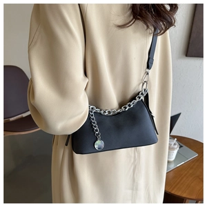 Detail of black crescent shoulder bag with silver chain and metal pendant on model