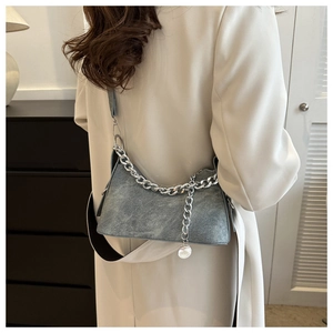 Grey suede-textured shoulder bag with silver chunky chain decoration worn by a model