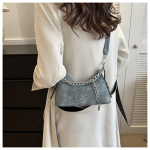 Detail of gray-blue washed fabric shoulder bag with bold silver metal chain accent