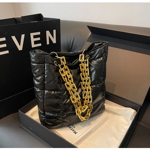 Detail of black quilted puffer tote bag featuring a shiny finish and bold gold chain strap