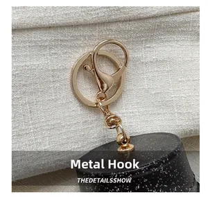 Detail shot of golden hardware hook and lobster clasp on a black matte shoulder bag