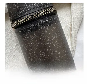 Close-up of black cylinder bag with silver glitter finish and metal zipper detail