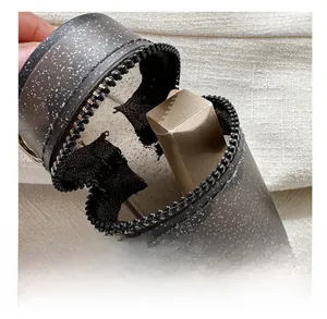 Detail view of mini translucent gray cylinder pouch showing interior capacity with zipper