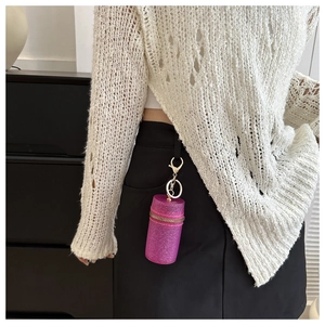 Detail of a sparkling hot pink mini cylindrical bag charm with gold zipper on a skirt