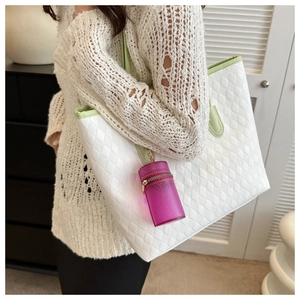 Detail of sequined purple cylinder charm on white quilted tote with green shoulder strap