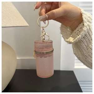 Close-up of pink glitter mini cylinder pouch with gold zipper and keychain detail