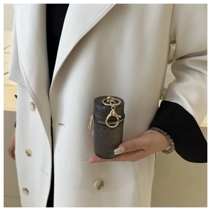 Detail of a mini cylindrical bag with black glitter finish and gold lobster clasp