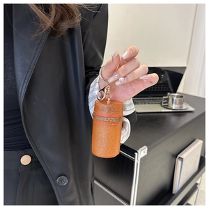 Close-up of orange glitter mini pouch with gold metal keychain held by person