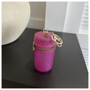 Close-up of mini rose red glitter cylinder bag with gold zipper and metal keychain
