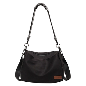 Black nylon tote bag with decorative wave-pattern handles and a long shoulder strap