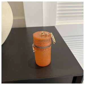 Macro shot of orange glitter resin mini cylindrical bag with gold zipper and lobster clasp
