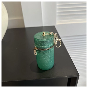 Close-up of glittery green cylindrical mini bag with gold zipper and lobster clasp keychain