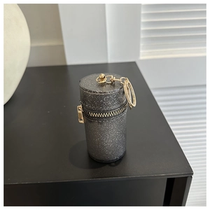 Detail of a mini black glitter cylinder coin purse with golden metal clip and keyring