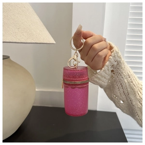 Detail view of mini pink glitter cylinder bag with gold lobster clasp keychain