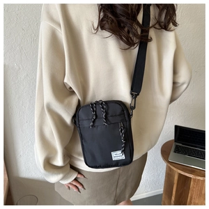 Close-up of black oxford cloth crossbody bag featuring adjustable strap and Hello Weekend label
