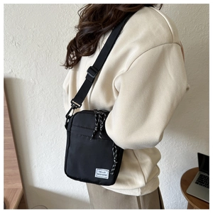Close-up of black nylon crossbody bag with adjustable strap and Hello Weekend label