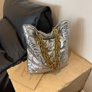 Silver quilted tote bag with gold chain strap on a stone base for a modern fashion style