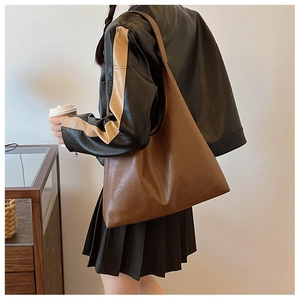 Gros plan d'un sac cabas en cuir marron avec une texture mate et une large bandoulière souple
