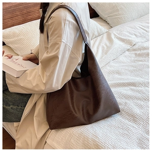 Détail d'un grand sac cabas vintage en cuir PU marron porté à l'épaule pour femme