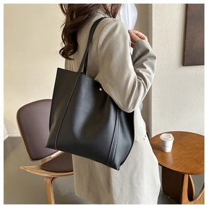 Detail shot of the black leather tote bag featuring durable double-stitch seams and rivets