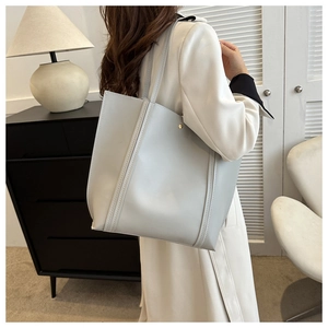 Large capacity grey PU leather tote bag worn by a model in a minimalist home setting