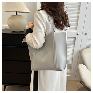 Detailed view of grey tote bag in textured faux leather with minimalist vertical stitching