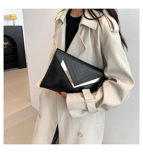 Détail de la pochette enveloppe noire avec bordure dorée en V et surpiqûres