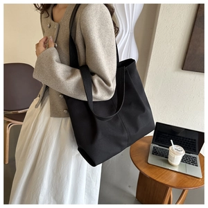 Bolso tote grande negro minimalista sobre mesa de madera con laptop y café