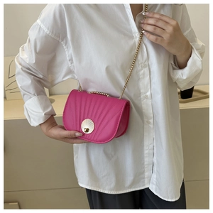 Fuchsia fanny pack with seashell lock and fine gold chain strap on white shirt