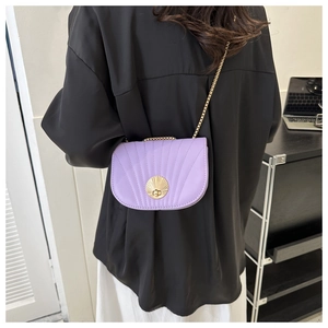 Detail of purple leather shell-shaped crossbody bag with gold lock and chain strap
