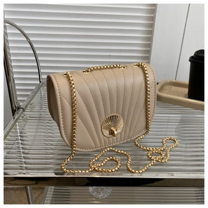 Detail of beige saddle bag featuring scallop quilting and gold circular twist lock