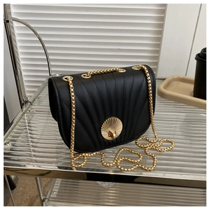 Detail of shell-shaped quilted stitching and gold shell-lock on black crossbody saddle bag