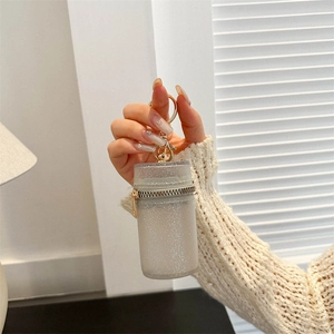 Glitter mini cylinder crossbody bag with golden chain and zipper shown in hand