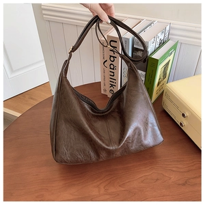 Close-up of dark brown hobo bag with natural pleated texture on a vintage wooden table