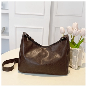 Detail of dark brown retro shoulder bag with smooth PU leather texture and gold zipper