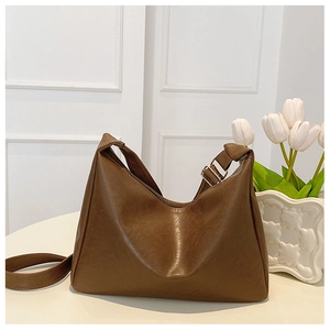Detail of a brown leather shoulder bag with zipper closure and adjustable silver buckle strap